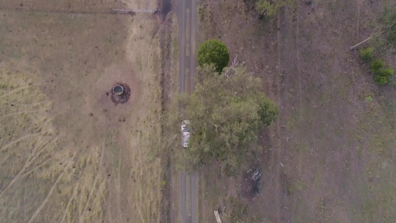 一个美丽的慢动作空中/无人机景观拍摄的农民的汽车行驶在尘土飞扬的内陆的土路上他/她的农舍。拍摄在惊人的4K分辨率视频素材