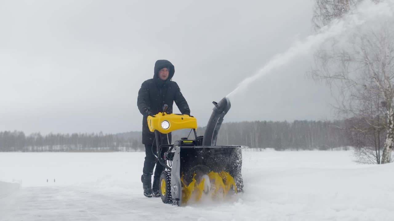 在院子里用机械犁除雪的人。慢动作视频素材