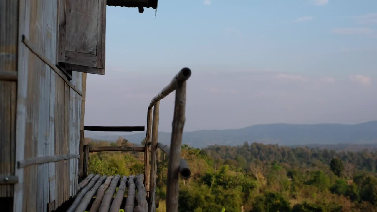 一位女游客穿上鞋子，走在木屋外，窗外是美丽的山景视频素材