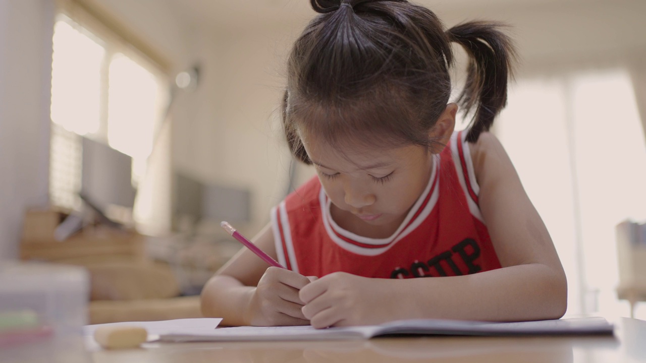 一个亚洲小女孩在家里学习写字视频素材