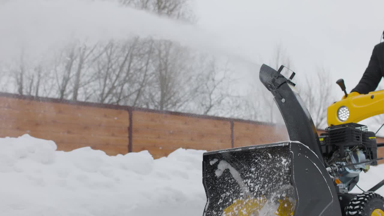 手动吹雪机的工作人员。下雪的冬天。人们用雪犁铲雪堆。吹雪机在行动。寒冷的天气。慢动作视频素材