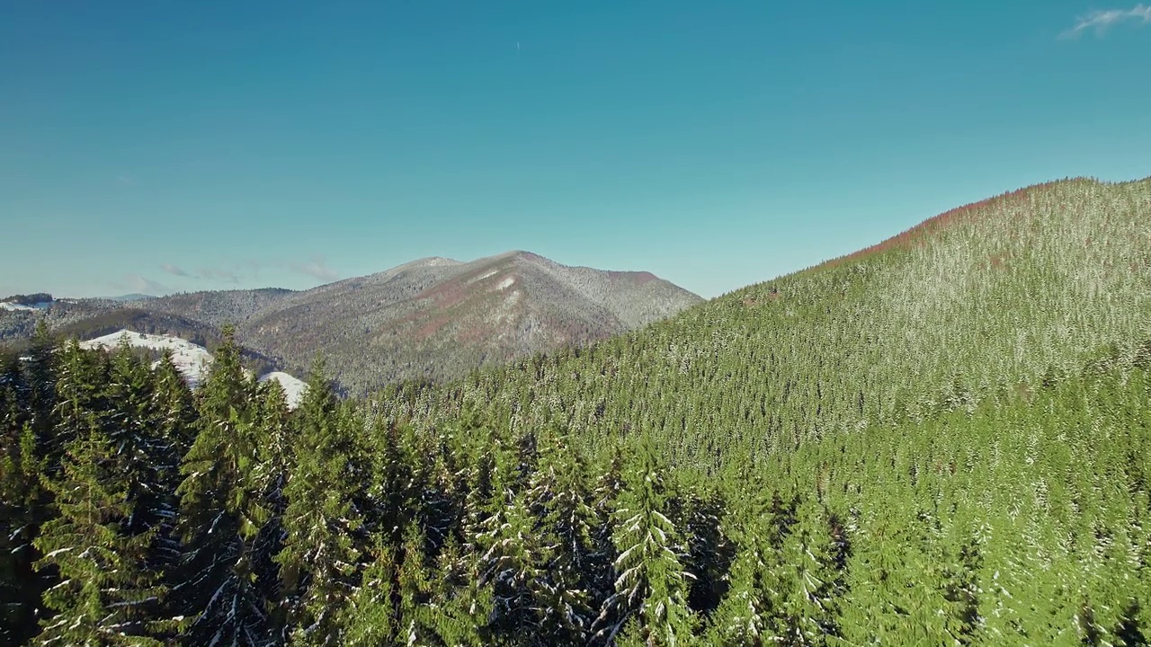 在阳光明媚的日子里山脉的全景。飞过冬天的森林。视频素材