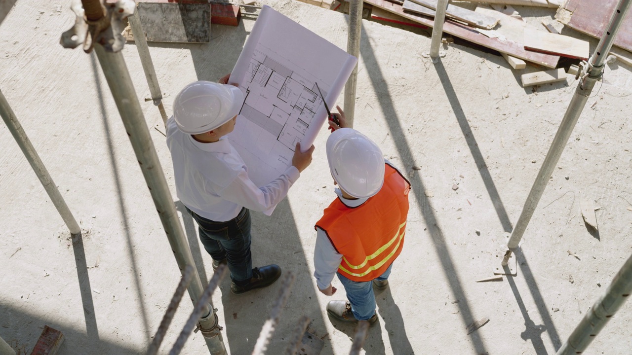 工程师和建筑师在建筑工地讨论和审查蓝图视频素材