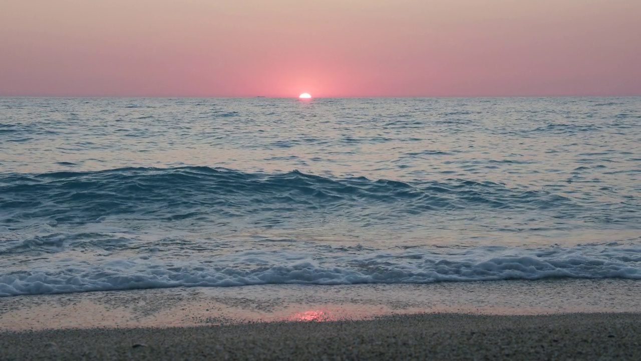 浪漫的海上日落背景。紫色的地平线上的天空没有云，海浪朝着卵石滩视频下载