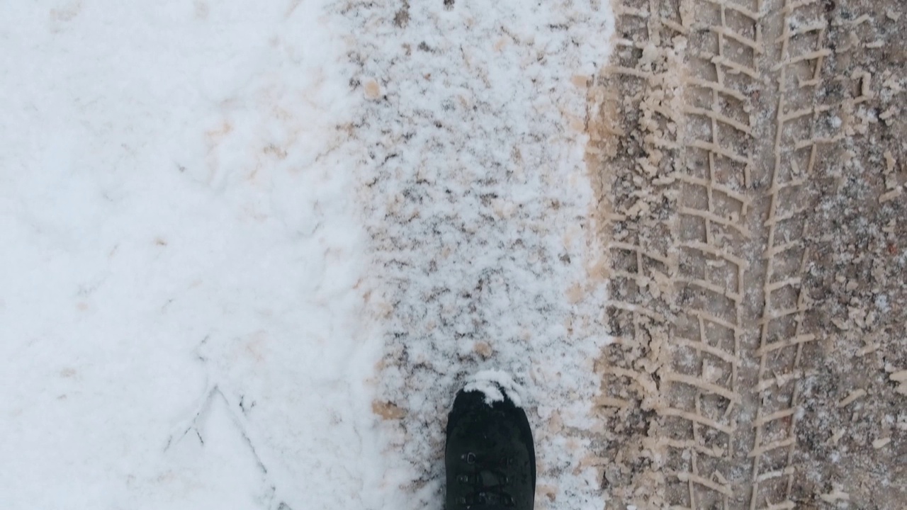 俯视图镜头显示，一名男子穿着靴子在雪地上行走视频素材