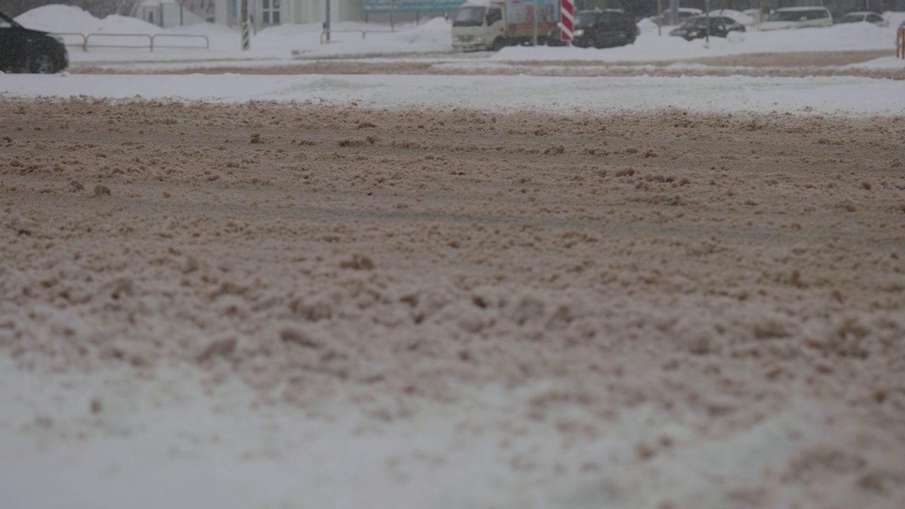 大雪期间的城市道路。汽车在冬天的泥和雪中行驶视频素材