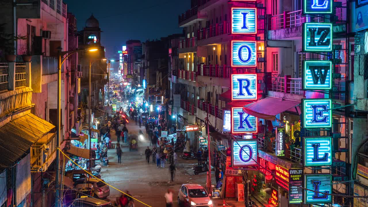 在印度德里市中心，主要集市街道的夜间延时视图，显示霓虹灯招牌，商店，交通和行人视频素材