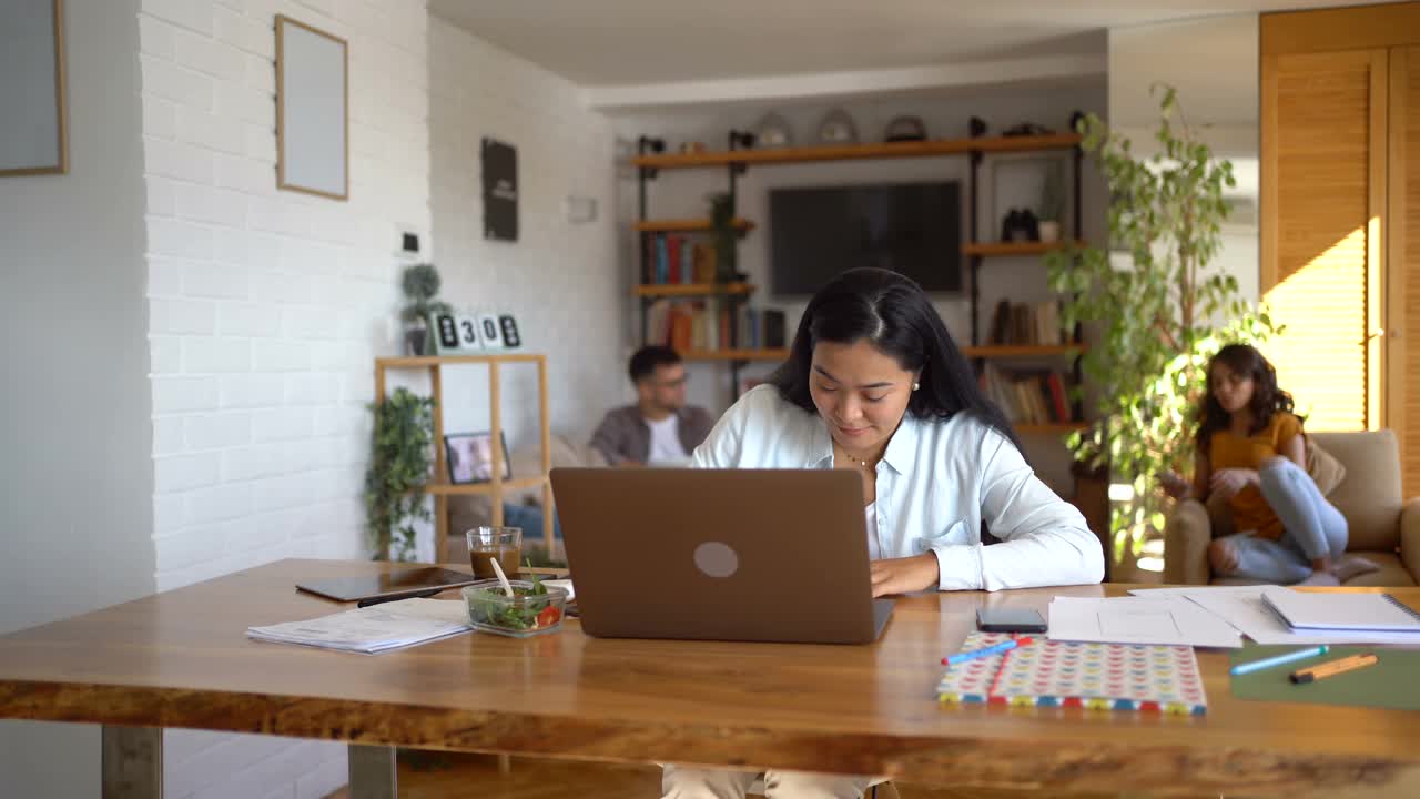 年轻漂亮的亚洲女人坐在她家庭办公室的办公桌前，做家庭财务。视频素材