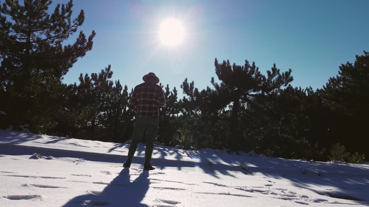 带着一架无人机飞过一个戴软呢帽的男人穿过松树的山峦。视频素材