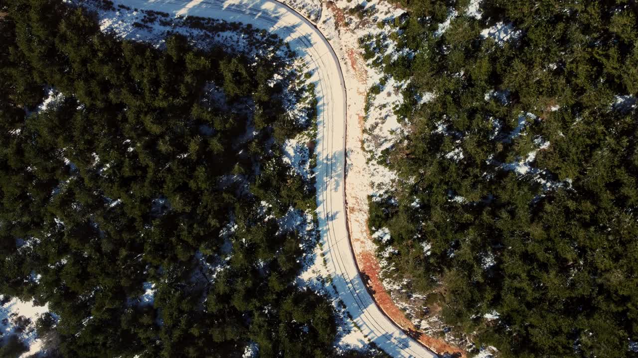 在土耳其的斯皮尔伊兹密尔山，从空中俯瞰冬天的积雪和松树之间弯曲的道路。视频素材