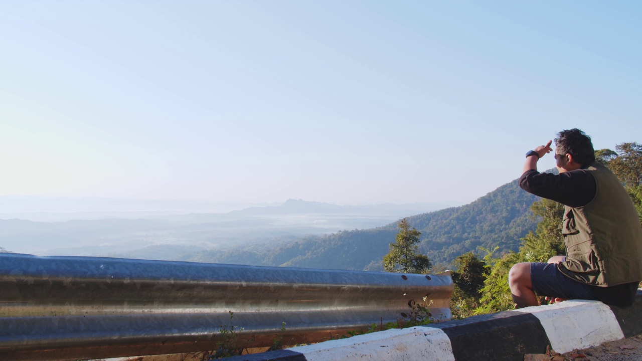 在泰国北部，夏天的时候，游客旅行者坐在热带自然山的山顶上，欣赏美丽的风景。视频素材