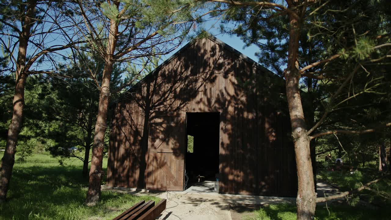 年轻的建筑工人或建筑师戴着安全帽，带着一份卷好的图纸离开现场的木质仓库，走向镜头，然后经过镜头视频素材