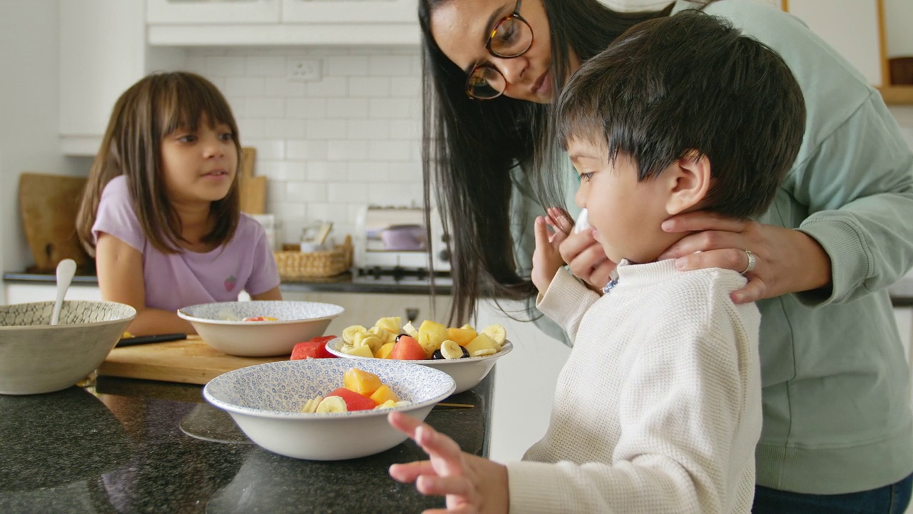 妈妈和孩子们在早上的厨房里吃新鲜的水果视频素材