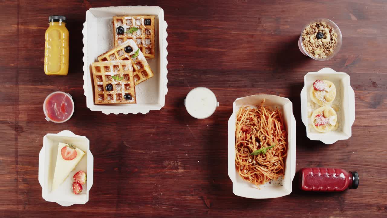 食品配送俯视图。午餐盒里有煮好的三文鱼、花椰菜和蔬菜沙拉，用一次性容器装外卖，放在木桌上。健康的饮食习惯。餐饮服务。视频素材