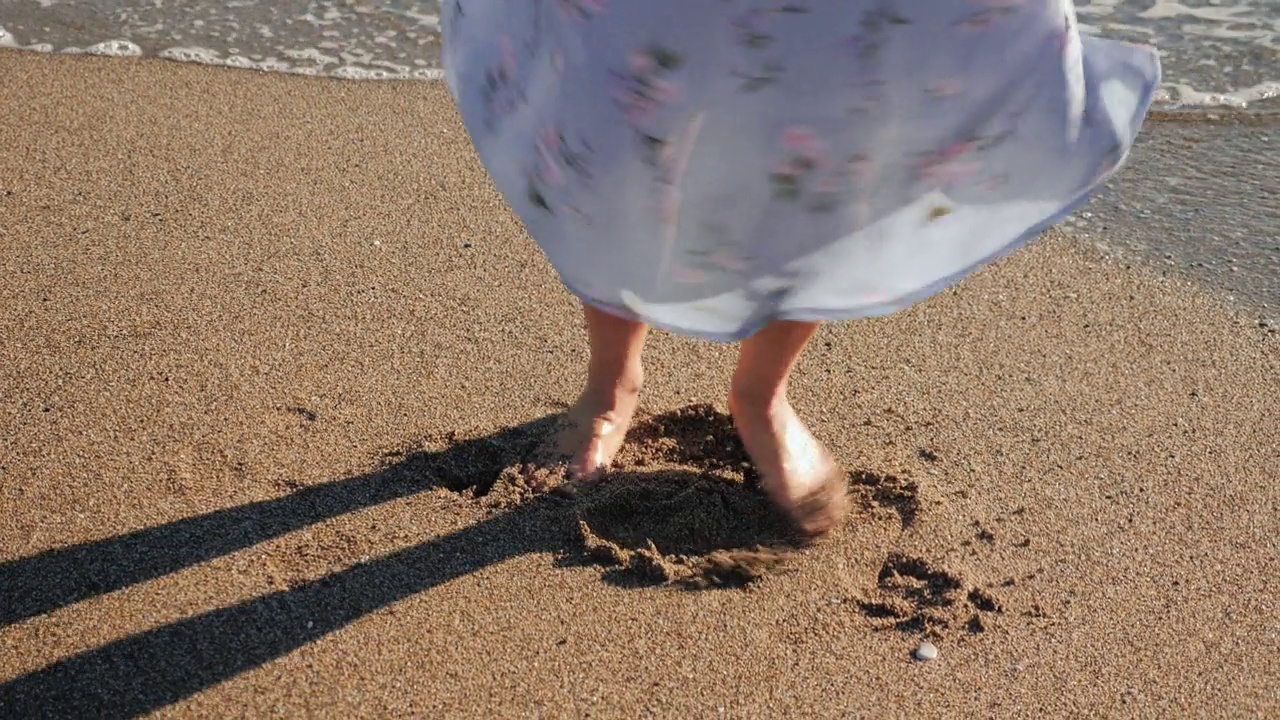 女人的脚在摇曳的夏装在沙滩上旋转。女人在夏日阳光明媚的日子里在海滩上跳舞，近距离的赤脚的腿。暑假和假期视频素材