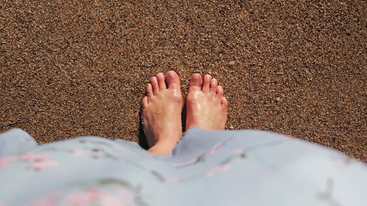 女性的脚踩在水边的沙子上。女人的腿在海水里。海浪拍打着沙滩上纤细的女性脚。夏天旅游度假视频素材