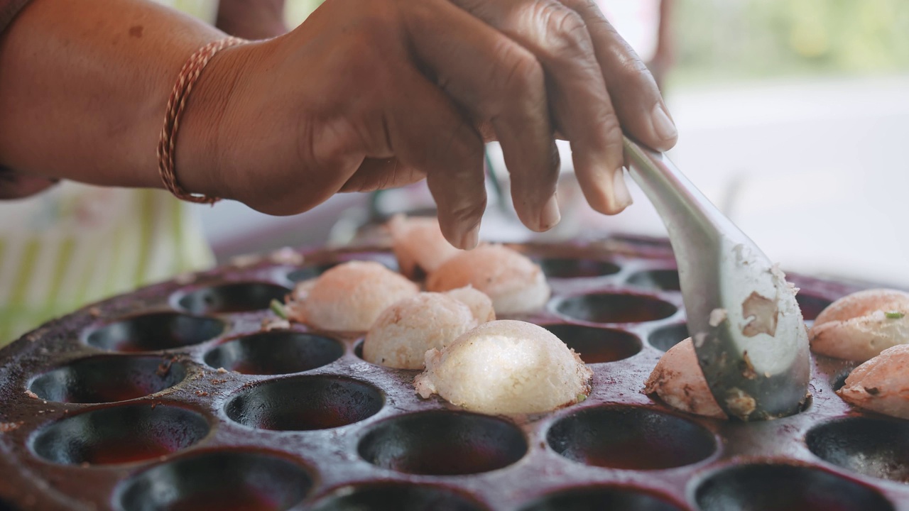 泰国传统街头小吃甜品Khanom Krok，椰奶煎饼在加工过程中混合糖和面粉，上面放小葱视频素材