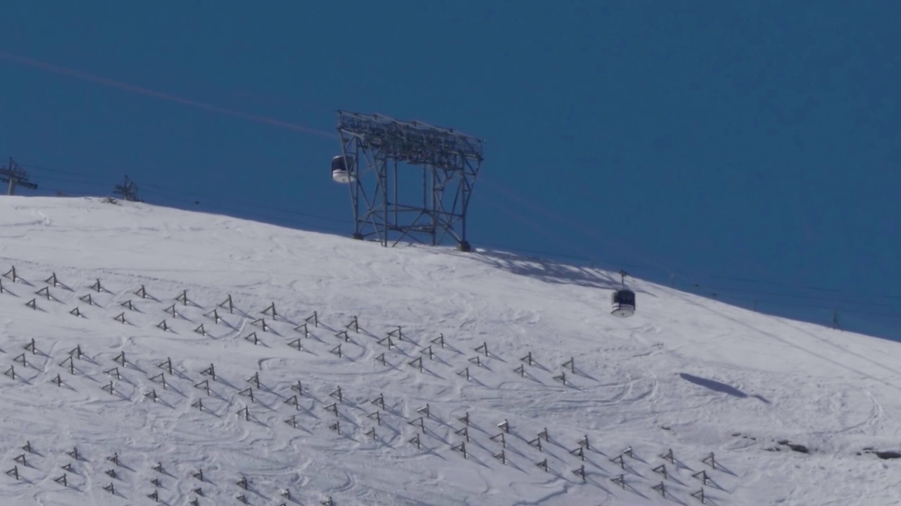 平移缆车爬上积雪覆盖的山坡，安装了防止雪崩的系统视频素材