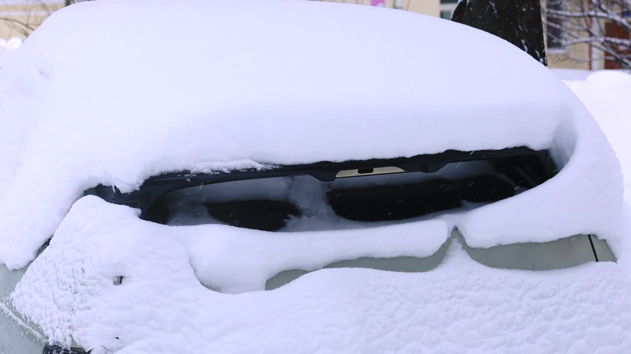 在俄罗斯的户外街道上，一辆车被雪压着视频素材