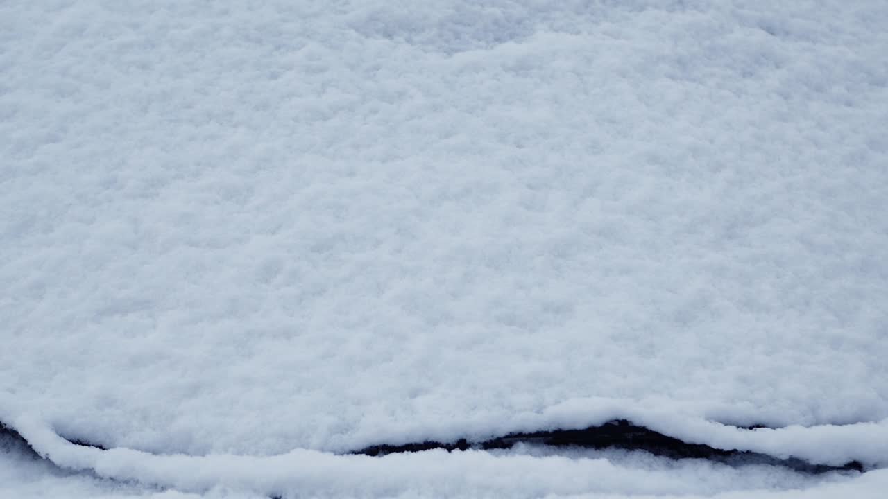 雨刷片清洁汽车的挡风玻璃上的雪，冬季暴风雪给汽车结冰。视频素材