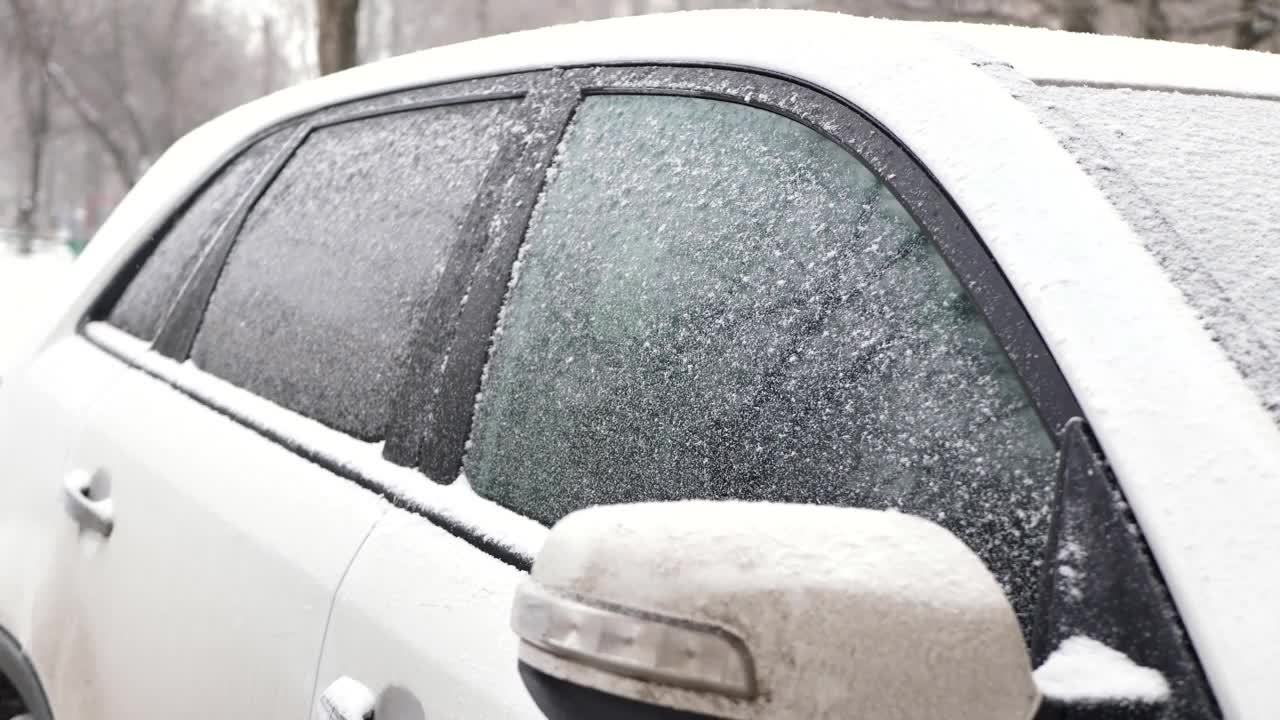 用手把车窗上的雪擦干净。在大雪中被雪覆盖的汽车视频素材