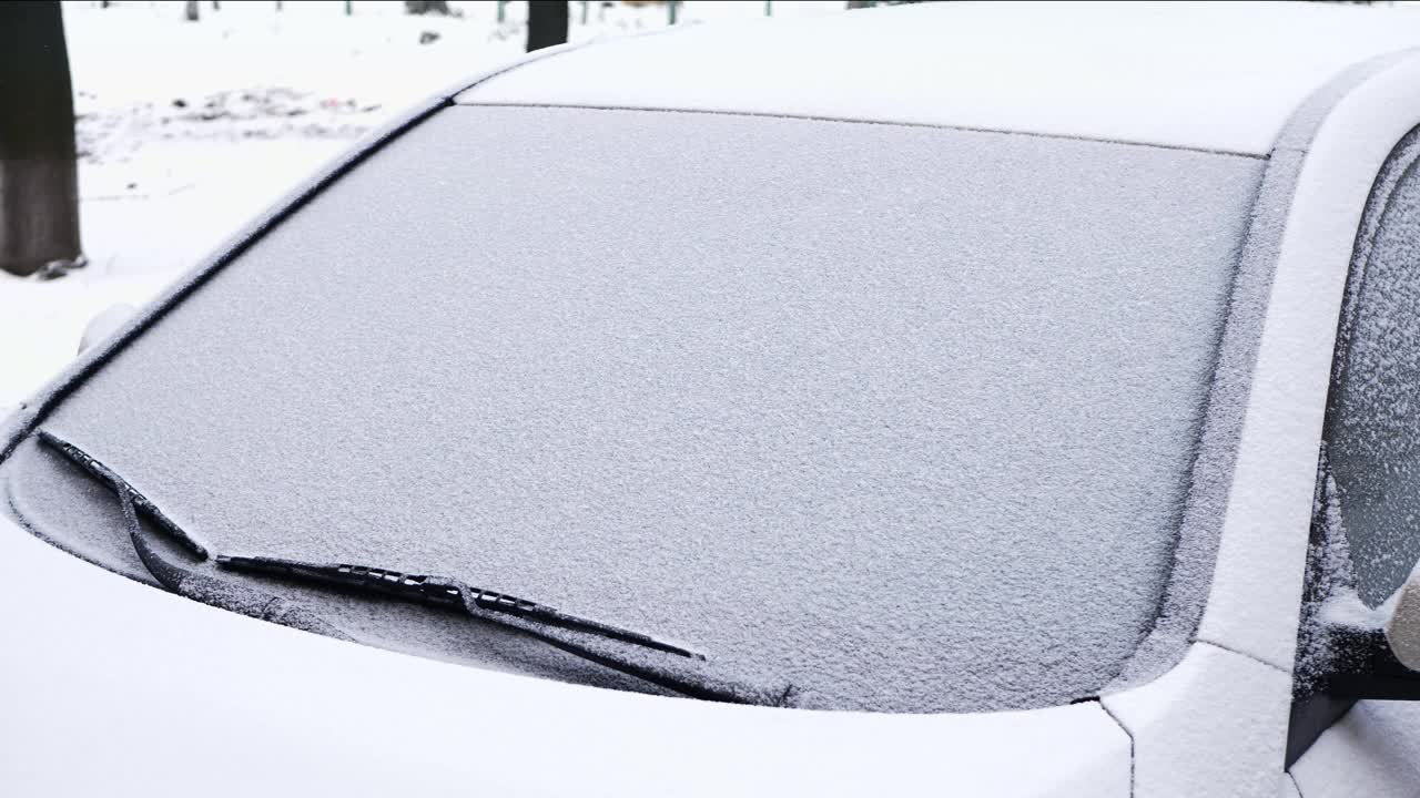 汽车刮水器可以清除车窗上的雪。雪片给汽车盖上了一层厚厚的雪视频素材