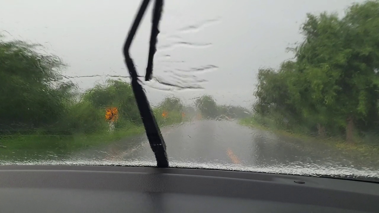 驾驶和雨点落在挡风玻璃上。视频素材