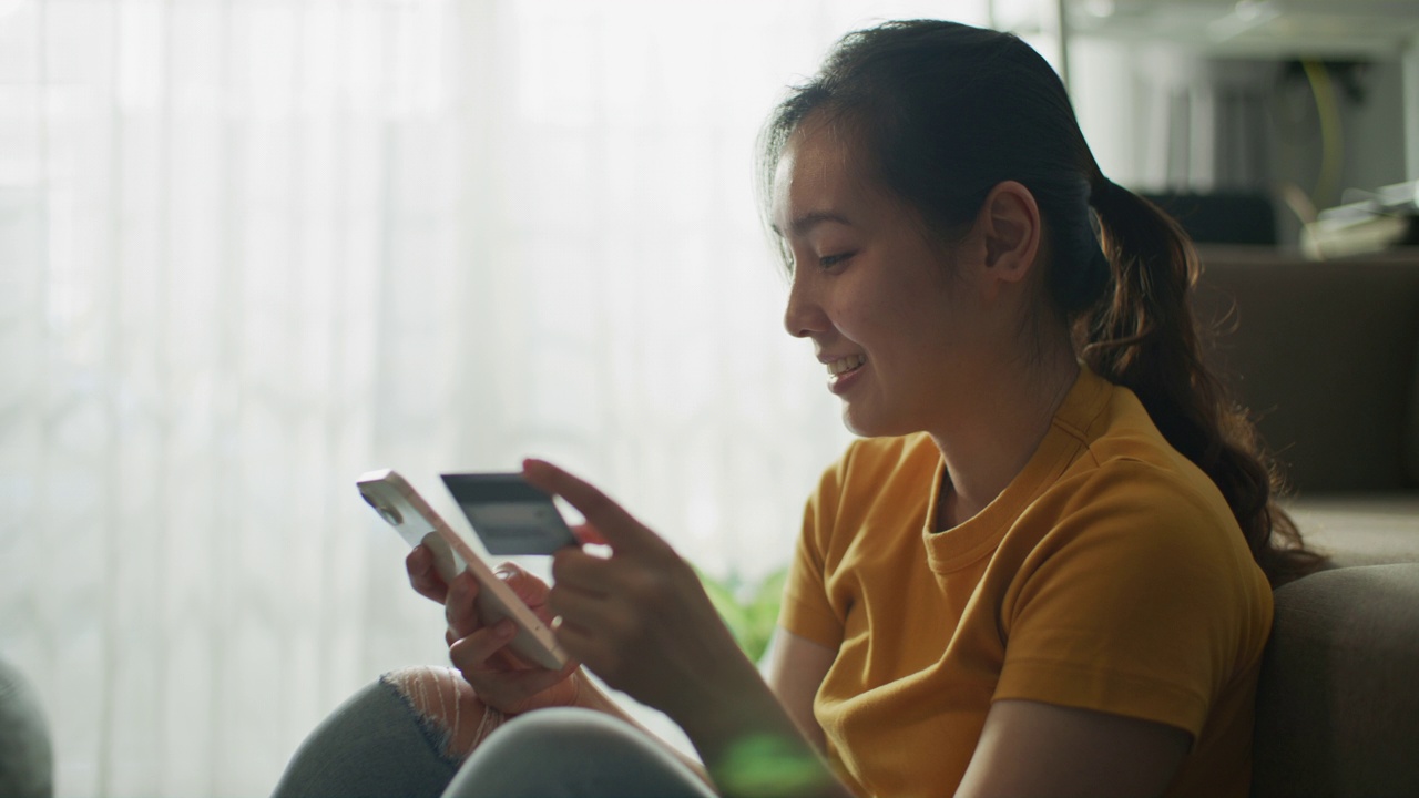 亚洲女性在家里用智能手机在线购物视频素材