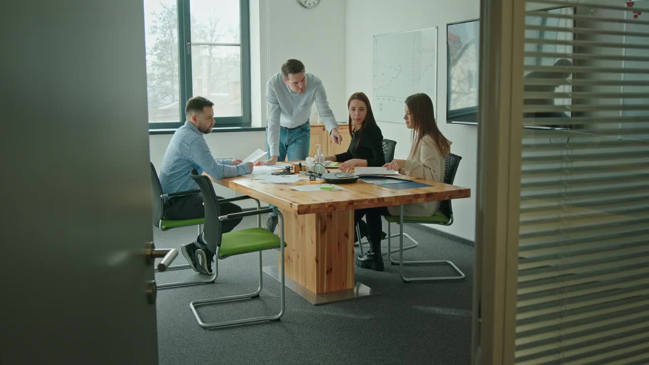 在一间现代化的办公室里，一群在公司工作的年轻人坐在谈判桌前，讨论一个新项目，一个人在白板上画了一幅图视频下载