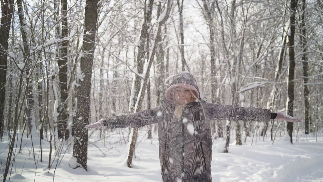 一个年轻的女人抛起一把雪，形成了一场雪。视频素材