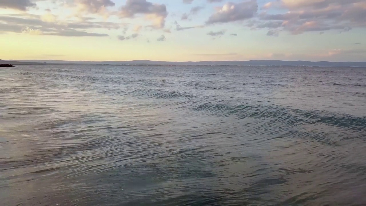 在日落的天空下，蓝色海浪的海面鸟瞰图。视频素材