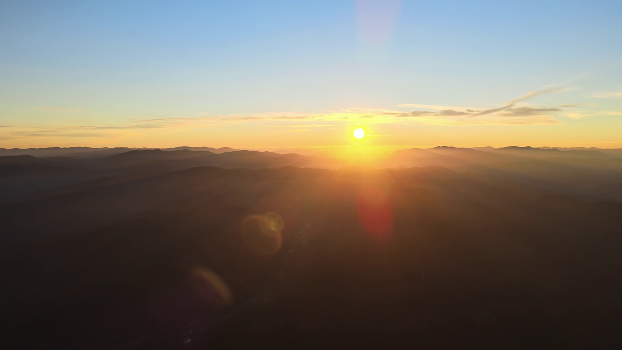 从空中俯瞰，日落时分，黑黝黝的小山和明亮的夕阳。傍晚朦胧的山峰和朦胧的山谷视频素材