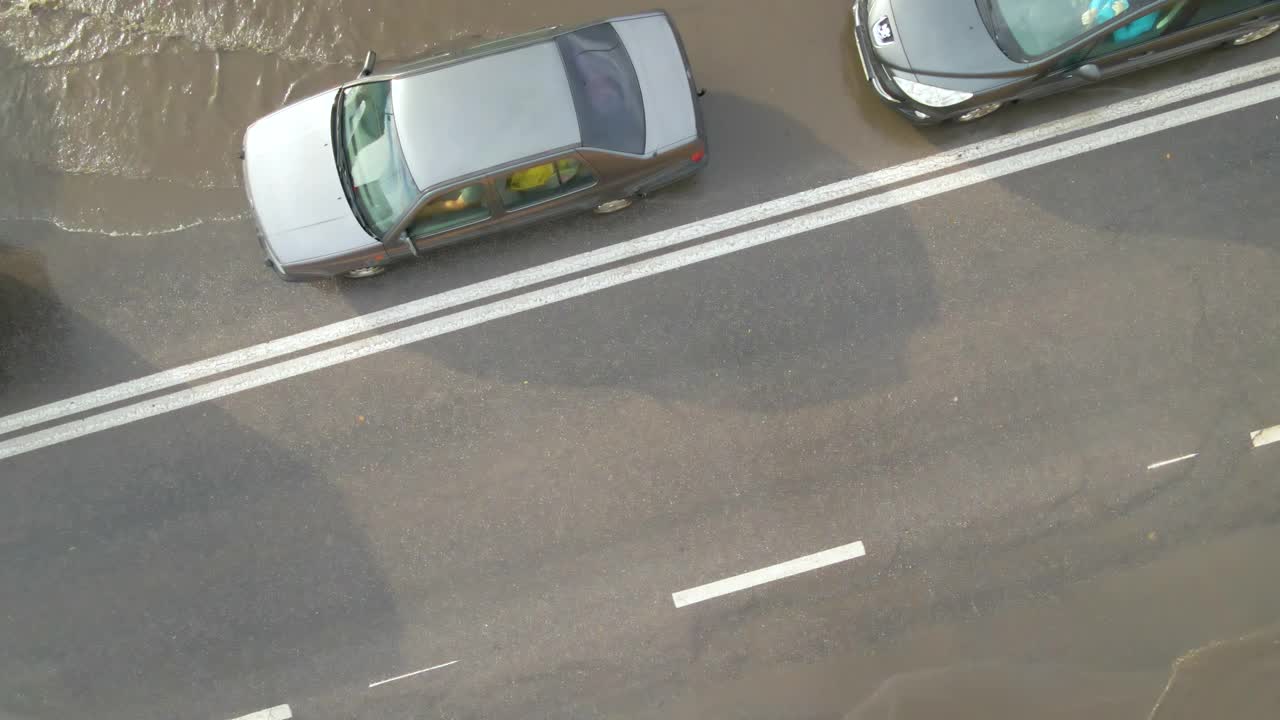 城市交通鸟瞰图，汽车行驶在暴雨后被淹没的街道上。道路排水系统的问题视频素材