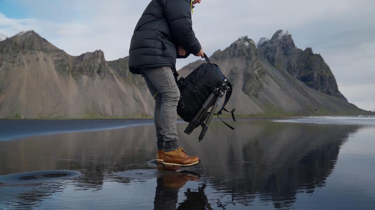 在维斯特拉霍恩山，一名徒步旅行者把背包搬到潮湿的海滩上视频素材