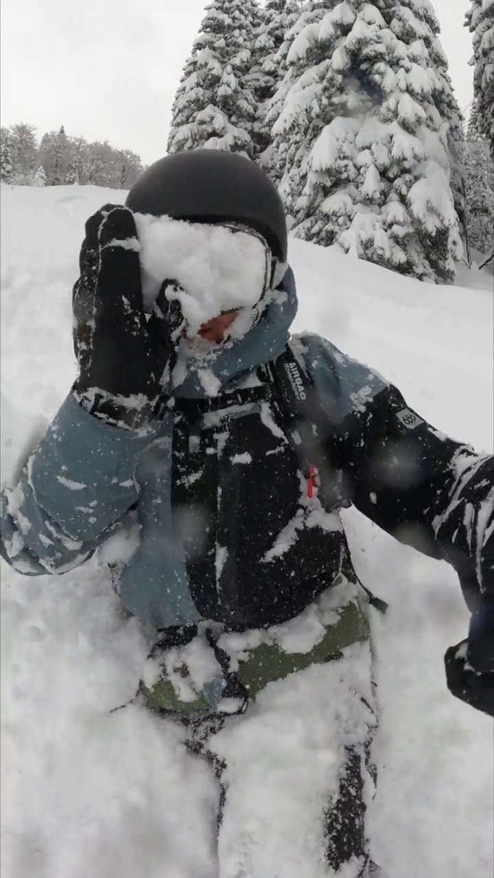 一名自由式滑雪板运动员从积雪覆盖的斜坡上滑下的垂直自拍视频素材