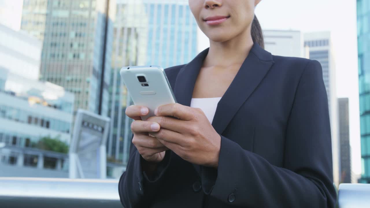 手机年轻的女商人用手机发短信的全景横幅。女士工作在办公室外背景通勤步行在城市街道视频素材