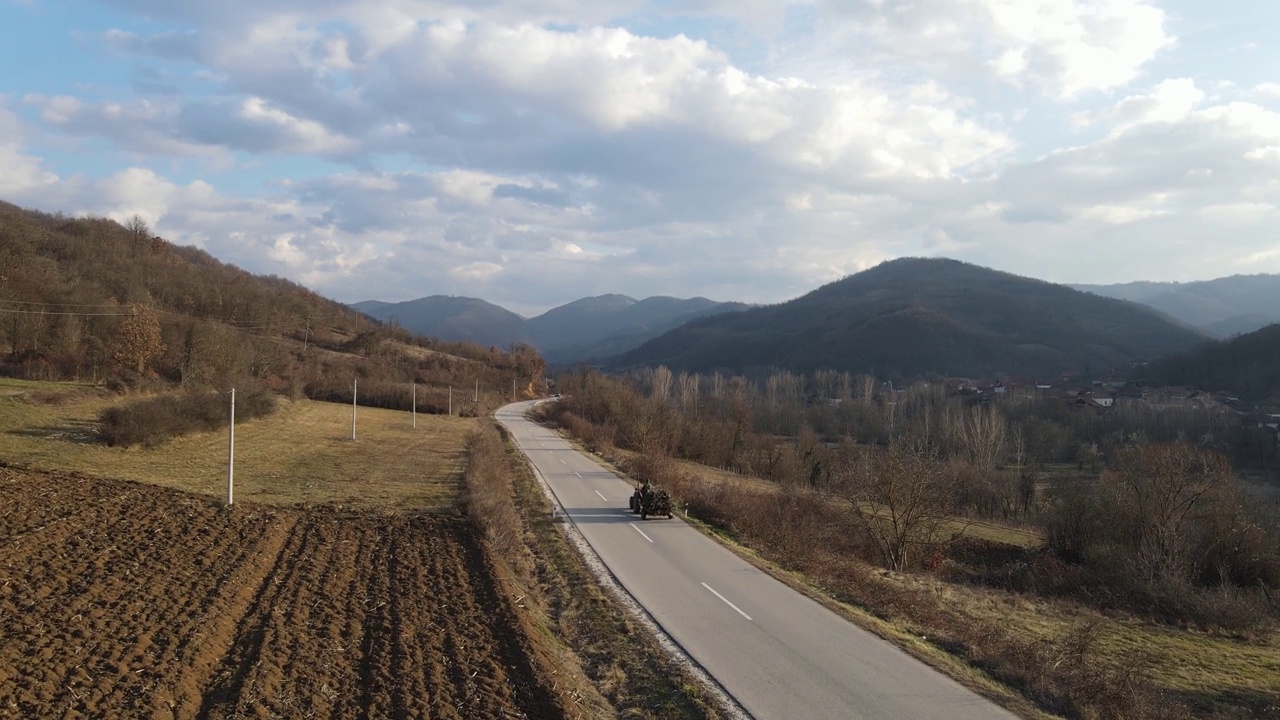 在塞尔维亚Knjazevac附近，秋冬的一天，拖拉机在公路上行驶，无人机在公路上的高角度航拍视频视频素材