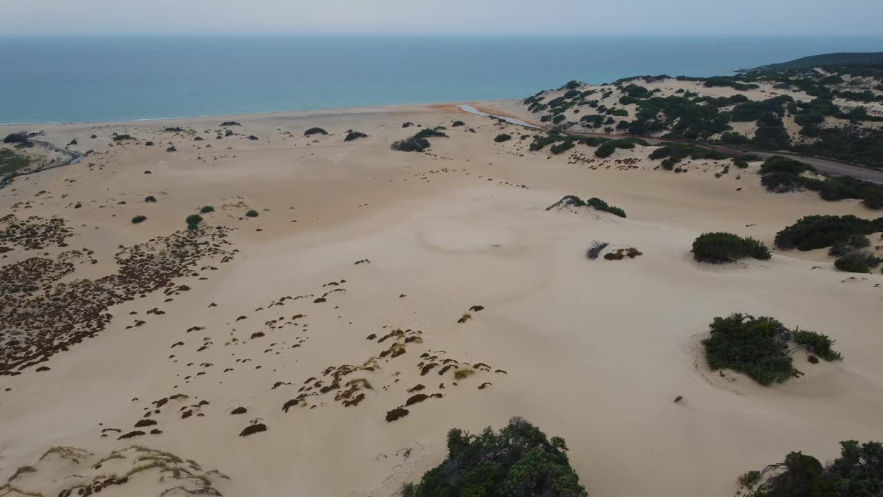 在意大利撒丁岛的一个自然沙丘景观，在一个旅游度假岛的海滨沙滩沙滩海湾与清澈的蓝色绿松石水。飞行在电影空中无人机空中视图飞行。视频素材