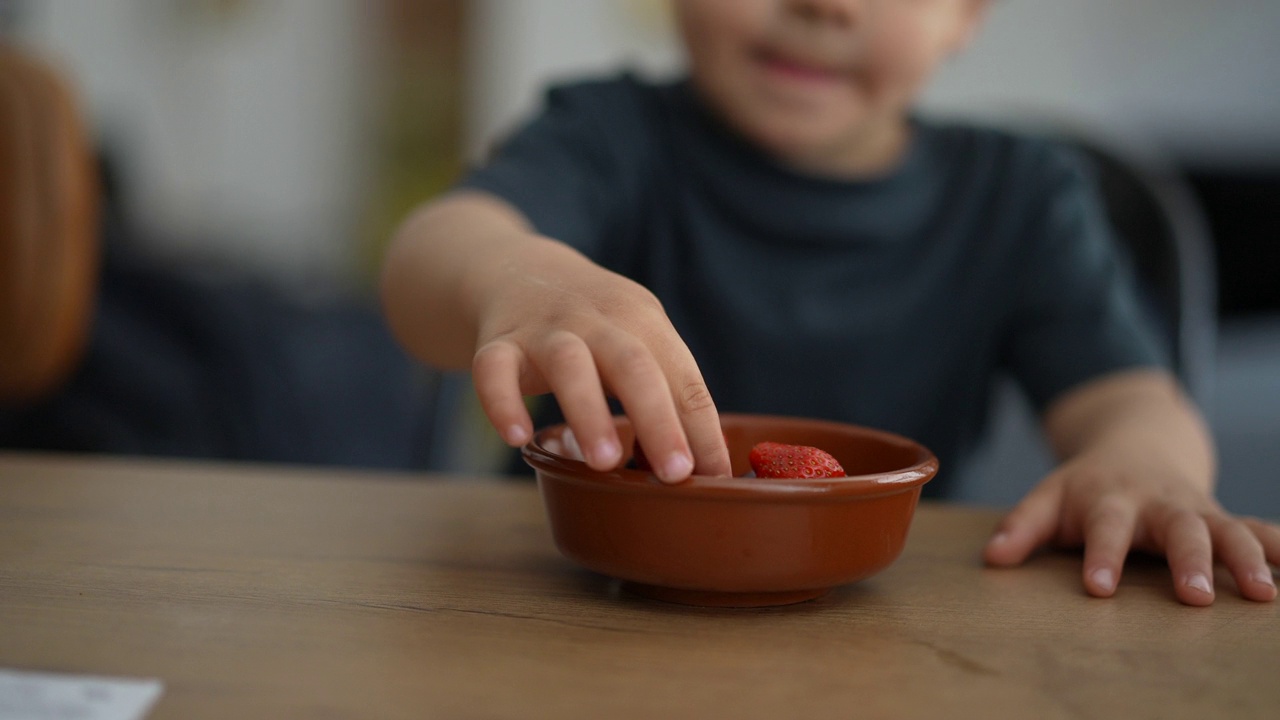 小男孩从碗里摘浆果，孩子吃水果视频素材