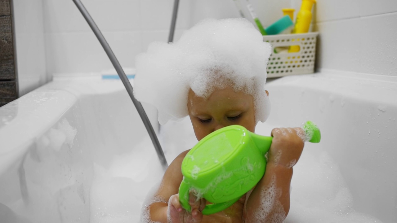 一个胖乎乎的孩子头上沾着泡沫，在白色的浴缸里洗澡视频下载