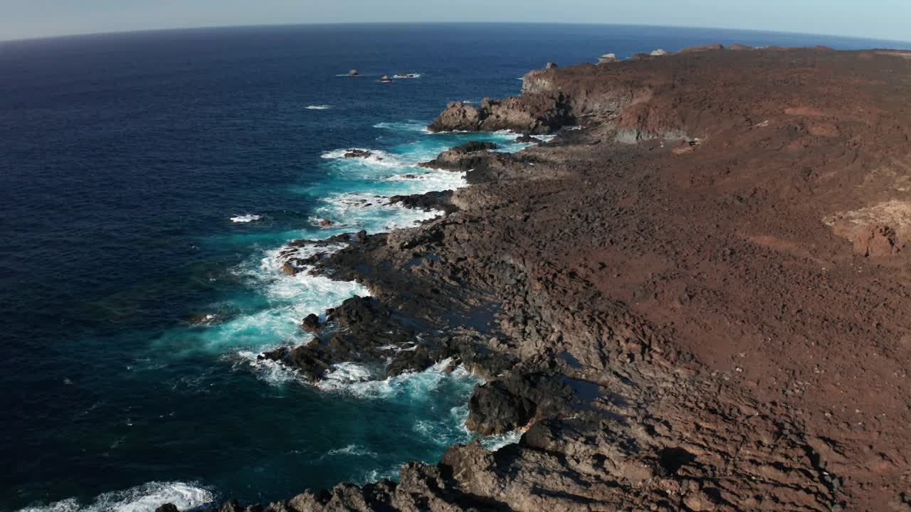 由凝固的熔岩和海浪组成的岩石海岸线的空中摄影车视频素材