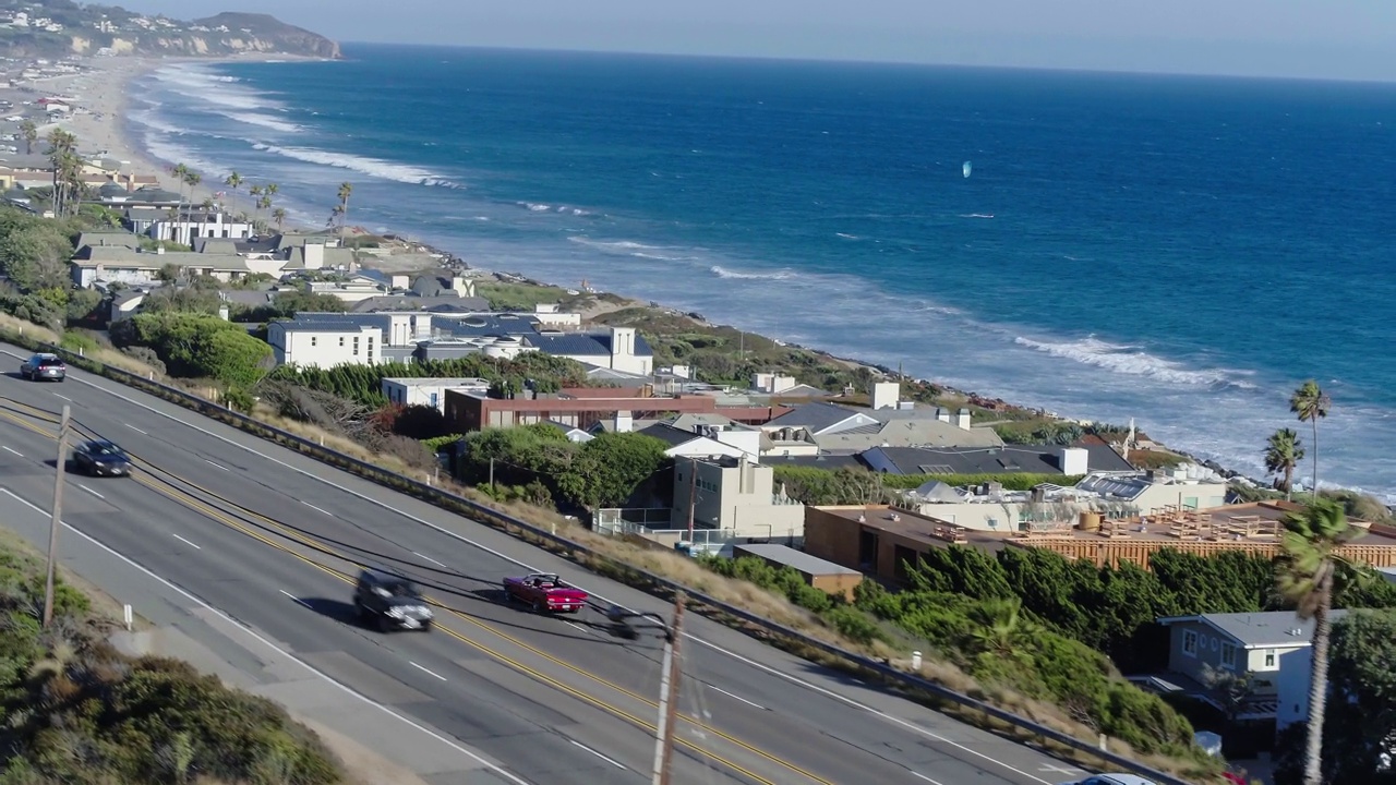 空中向前平移镜头的汽车在道路上的海滩，无人机飞行在风景在阳光明媚的一天-马里布，加利福尼亚视频素材