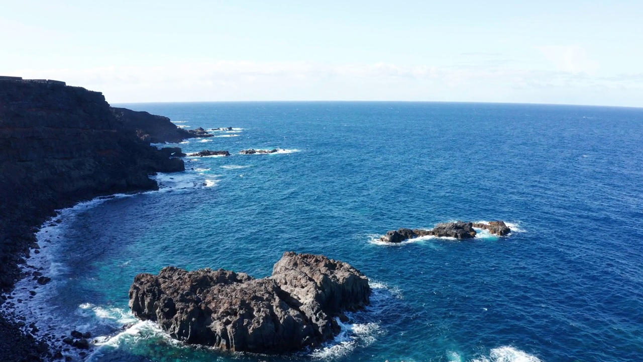 空中摄影车在蔚蓝的翡翠海洋和火山海岸硬化的熔岩上视频素材