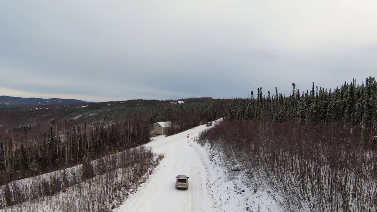 空中向前拍摄的汽车在积雪的道路上在森林-费尔班克斯，阿拉斯加视频素材