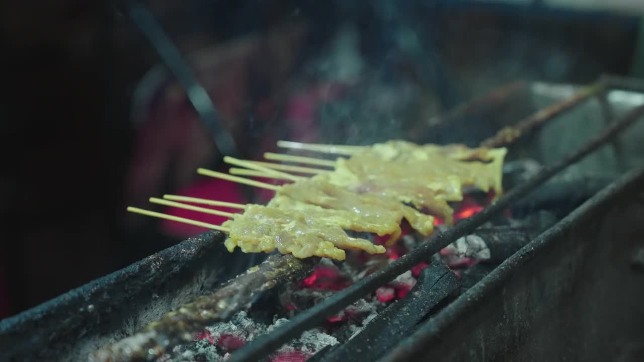 曼谷的中国城。靠近猪肉沙爹在热炭烤架上，烤猪肉在晚上。视频素材