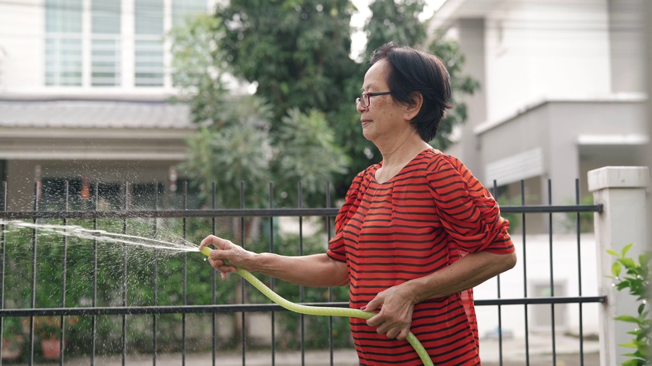 高级妇女在家里给室外室内植物浇水。视频素材