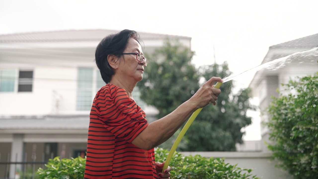 高级妇女在家里给室外室内植物浇水。视频素材