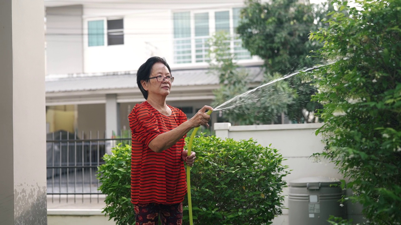 高级妇女在家里给室外室内植物浇水。视频素材