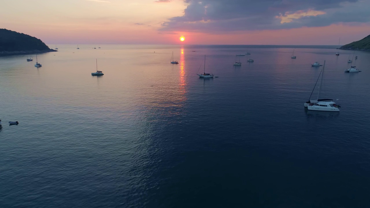 海面上五颜六色的日落与帆船航拍无人机飞越普吉岛海面反射太阳金色的光在水面上日落海洋海景夏季和旅游度假的概念视频素材