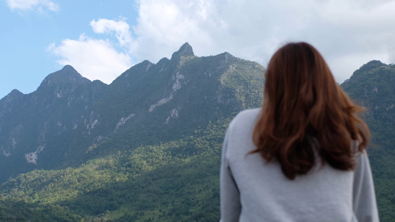 模糊的后视图，一个女性旅行者看着一个美丽的山景视频素材